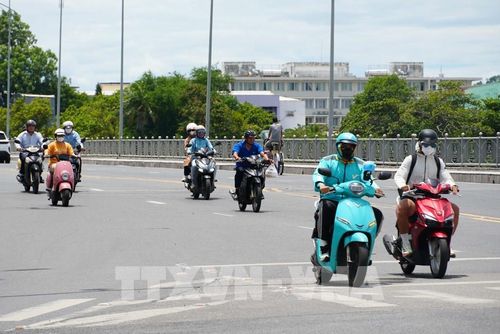 Người dân tham gia giao thông trên cầu Phú Xuân, thành phố Huế, mặc đồ bảo hộ để giảm tác động nắng nóng. Ảnh: Nguyên Lý - TTXVN