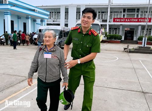 Công an xã Vĩnh Thuận hỗ trợ người cao tuổi là thân nhân liệt sĩ đến điểm thu nhận mẫu ADN. Ảnh: ÚT CHUYỀN