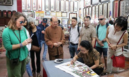 Khách du lịch quốc tế tham quan tìm hiểu di sản Nghề làm tranh dân gian Đông Hồ tại gia đình Nghệ nhân Ưu tú Nguyễn Thị Oanh (phường Thuận Thành).