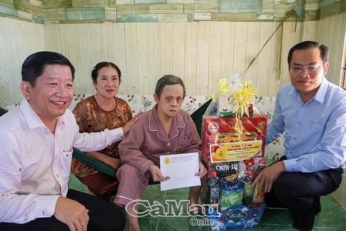 Ông Ngô Vũ Thăng, Phó Chủ tịch UBND tỉnh Cà Mau (bìa phải), tặng quà anh Trần Thanh Bình, là NNCÐDC tại Ấp 2, xã Ðầm Dơi.