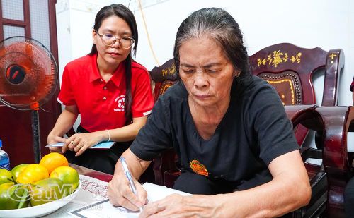 Mẹ chị Trần Thị Thu Hương được cán bộ hướng dẫn, hỗ trợ thực hiện thủ tục tại nhà.