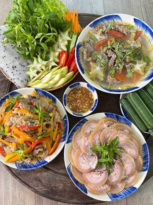 Bắp bê cuộn hấp mềm ngọt, cuốn cùng bánh tráng, rau thơm, khế và chuối xanh rồi chấm mắm nêm đậm đà. Bên cạnh đó là đĩa bê xào sả ớt thơm lừng, bát canh bò nấu khế chua thanh và vài chiếc nem chua ăn kèm. Các món có vị đậm, cay, chua được cân bằng bằng rau sống và bát canh nóng, tạo thành một mâm cơm nhiều hương vị nhưng không quá ngấy.
