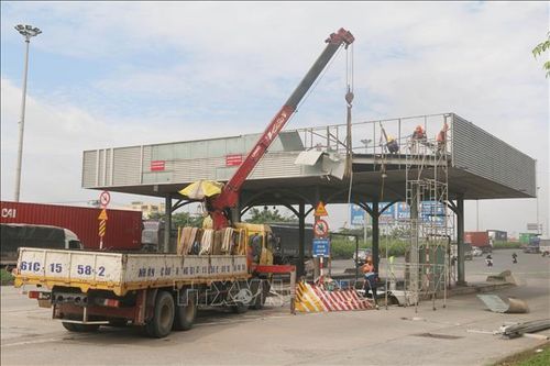 Máy móc, nhân lực thực hiện tháo dỡ trạm thu phí cầu Đồng Nai. Ảnh: Công Phong/TTXVN