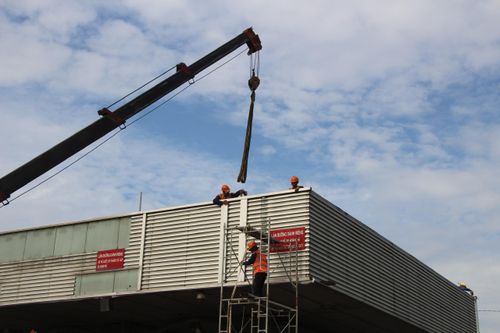 Từng nhóm công nhân dàn trải ra các khu vực, người tháo dỡ mái, người tháo các thiết bị bên trong, người điều khiển máy móc...