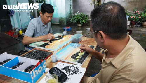 Anh Đàm Việt Cường (bên trái) và Hoàng Hữu Tấn đảm nhiệm việc ghép những mẩu than phù hợp vào nền tranh. (Ảnh: Tiến Thắng)