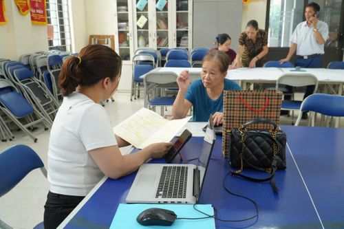 Người dân được cán bộ hướng dẫn đối chiếu giấy tờ, cập nhật dữ liệu đất đai. Ảnh: Tùng Lâm