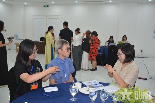  Hai bạn sinh viên khiếm thính (bên trái) hướng dẫn khách mời giao tiếp bằng ngôn ngữ ký hiệu.