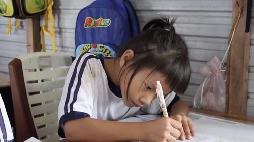 Dù có đi làm cùng mẹ tới khuya, hôm sau các em vẫn cố gắng làm bài tập đầy đủ. Ảnh: Phương Thy.