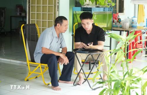 Các thành viên Tổ công nghệ số cộng đồng hướng dẫn người dân thực hiện dịch vụ công trực tuyến. (Ảnh: Hữu Duyên/TTXVN)