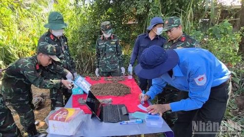 Cẩn thận lưu thông tin phục vụ giám định ADN tại nghĩa trang tạm thời chiến xã Nhuận Phú Tân. (Ảnh: HOÀNG TRUNG)