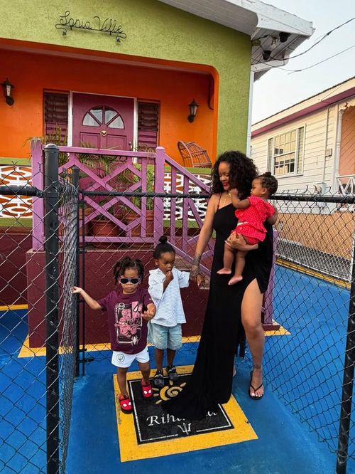 Rihanna rạng rỡ bên các con khi cả gia đình đứng cạnh một tấm biển trên mặt đất có dòng chữ “Rihanna”.
