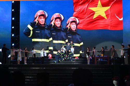 Cao trào vở kịch "Phía sau bình yên": chân dung ba chiến sĩ cứu hỏa hy sinh khi làm nhiệm vụ được phóng lớn trên màn hình LED, phía dưới là đội hình diễn viên tái hiện khoảnh khắc gia đình, đồng đội tiễn đưa