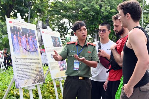 Cán bộ Công an Hà Nội giới thiệu với du khách nước ngoài về chuyên án ma túy thế kỷ Xiêng Phênh – Vũ Xuân Trường tại không gian triển lãm ảnh trên phố đi bộ.