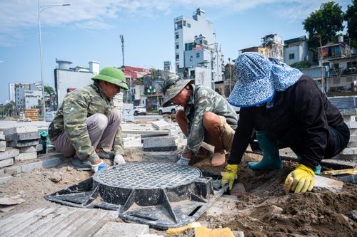 Trước cổng Bệnh viện Nhi Trung ương, đơn vị thi công đang khẩn trương thi công lát đá vỉa hè và lắp đặt hố ga.