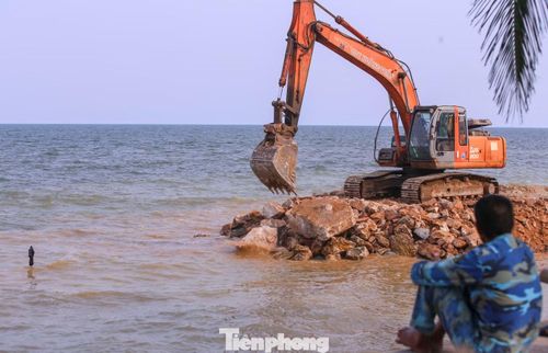 Người dân địa phương chia sẻ bờ kè bị sạt lở đã ảnh hưởng lớn đến cuộc sống và hoạt động du lịch. Họ mong dự án sửa chữa bờ kè biển Hải Tiến này sớm được hoàn thành, để người dân yên tâm hơn mỗi khi có mưa bão. Trong ảnh, nhà thầu đắp đường công vụ ra khu vực bờ biển để "cứu" bờ kè bị sóng đánh tan.