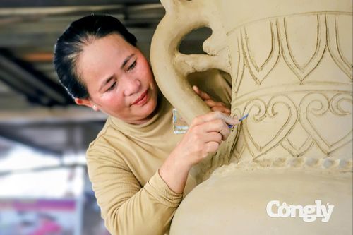 Chị Mỹ Xinh tạo hoa văn cho cặp bình gốm cao trên 2,2 mét trước khi chuyển vào lò nung.
