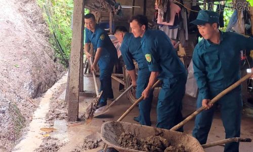 Lực lượng dân quân kịp thời xúc dọn đất, đá, hỗ trợ gia đình ông Hoàng Hữu Khải ở thôn Vực Tuần khắc phục hậu quả thiên tai.