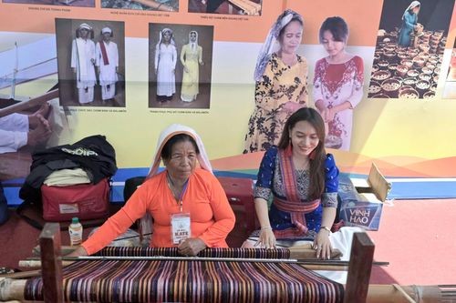 Du khách thích thú chụp ảnh bên khung dệt cùng Nghệ nhân Mã Thị Thuận tại lễ hội Ka Tê