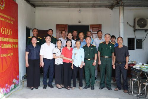 Các đại biểu tại lễ bàn giao chụp hình lưu niệm tại nhà của bà Hoàng Thị Lam. Ảnh: Minh Khiêm