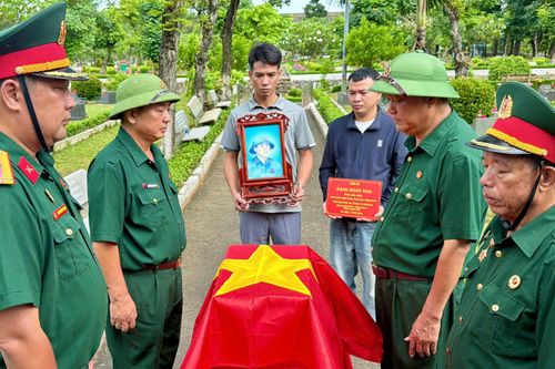  Nghi thức phủ Quốc kỳ lên hài cốt liệt sĩ Đặng Doãn Ngọ. Ảnh: HOÀNG HÙNG 