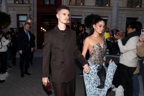 Kim sánh đôi Romeo tại Paris Fashion Week tháng 3/2025, khi gia đình Beckham tới ủng hộ bộ sưu tập mới của Victoria. Cô chọn thiết kế xuyên thấu in hoa, phần thân dựng phom và tà vải lớn, phối cùng quần cạp gập.