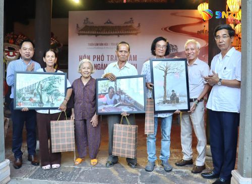 Lãnh đạo phường Hội An (ngoài cùng bên phải) và lãnh đạo Trung tâm Bảo tồn di sản văn hóa thế giới Hội An (ngoài cùng bên trái) trao quà động viên một số người dân Hội An là những người đang âm thầm lan tỏa vẻ đẹp di sản này. Ảnh: QUỐC TUẤN