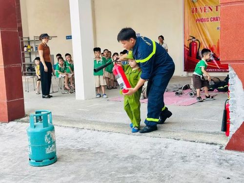 Cán bộ, chiến sĩ hướng dẫn trẻ thực hành sử dụng bình chữa cháy dưới sự giám sát, hỗ trợ trực tiếp.
