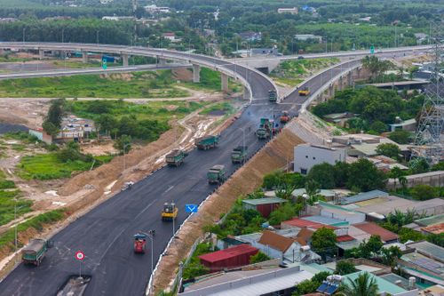  Hàng chục xe ben chở bê tông nhựa nóng xếp hàng chờ tới lượt đổ những lớp nhựa cuối cùng trên 2 nhánh đường dẫn. 