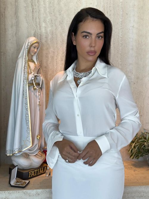  Trong ngày trọng đại, Georgina diện bộ váy bằng lụa faille trắng, kết hợp giày satin cùng màu. Điểm nhấn trên đôi giày là chi tiết khóa hình móng ngựa bằng bạc, đặc trưng của Gucci. Cô hoàn thiện diện mạo bằng vòng cổ Chopard Garden of Kalahari, nổi bật với viên kim cương 50 carat màu D, độ tinh khiết cao. Ronaldo chọn bộ vest cotton màu be nhạt được may riêng, đi cùng đôi giày lười đồng bộ. Các con của cặp đôi cũng mặc trang phục được thiết kế riêng để xuất hiện trong buổi lễ. 