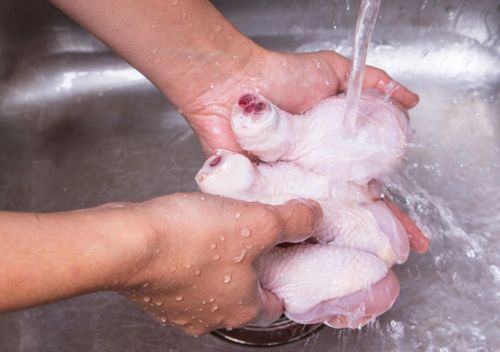 Rửa thịt gà sống dưới vòi nước không giúp loại bỏ hoàn toàn vi khuẩn mà còn có thể làm mầm bệnh phát tán qua các giọt nước, gây nhiễm khuẩn chéo trong bếp. Ảnh: Shutterstock.