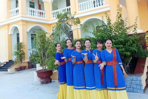 Nụ cười rạng rỡ của các thành viên đội múa Chăm trong sắc phục xanh thướt tha trước giờ biểu diễn