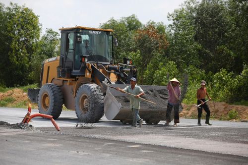 Công nhân, máy móc chia thành nhiều mũi thi công các hạng mục như thảm nhựa, cống rảnh, đắp đất trên công trường.