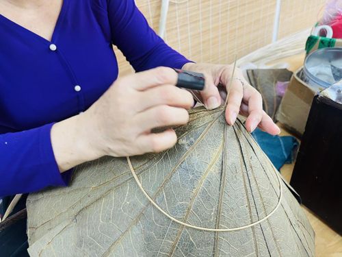 Từng đường kim, mũi cước đòi hỏi sự khéo léo và lực tay chuẩn xác để giữ cho phiến lá sen mềm dẻo không bị rách. (Ảnh: H.T)