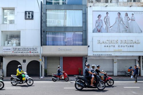 Tuy nhiên, một vài thương hiệu cũng tận dụng làn sóng trả mặt bằng trên đường Hồ Văn Huê để tìm đến mở cửa hàng, đơn cử như thời trang thiết kế nữ Dé Kaen vừa chuyển cửa hàng từ đường Hoa Lan (phường Cầu Kiệu) về đây hơn một tháng nay. Trong hình, Rachis Bridal ngay kế bên đã rời đi, còn thương hiệu Lumiere Weddings vẫn duy trì kinh doanh tại "thủ phủ" váy cưới này.