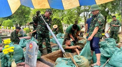 Với các phần mộ bị ngập nước, cán bộ, chiến sĩ Bộ Chỉ huy quân sự tỉnh phải dùng gáo, ống hút "tự chế" để rút nước trong mộ ra ngoài. (Ảnh: LÊ LAN)