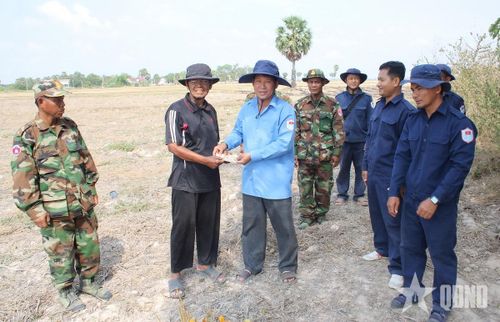 Thượng tá Võ Thành Dẫn (thứ ba, từ trái sang) trao tiền hỗ trợ người dân cung cấp thông tin về liệt sĩ tại huyện Ba Phnum, tỉnh Prey Veng (Campuchia). Ảnh: TRUNG THẮNG
