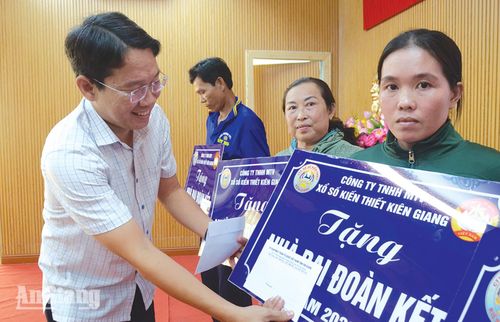 Chủ tịch UBND xã Tân Hội Nguyễn Minh Ngọc trao bảng tượng trưng bàn giao nhà Đại đoàn kết cho các hộ dân. Ảnh: VĨ AN