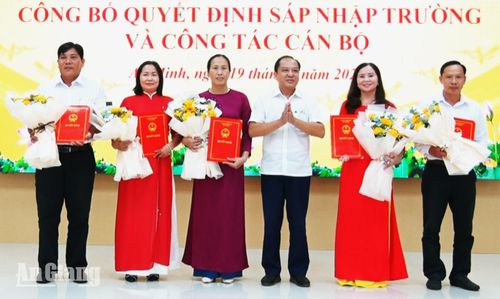 Bí thư Đảng ủy xã An Minh Nguyễn Đức Chín (thứ ba, từ phải qua) trao các quyết định sáp nhập trường học.