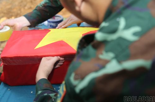 Thực hiện nghi lễ phủ Quốc kỳ lên linh cữu liệt sĩ Bùi Văn Tự.