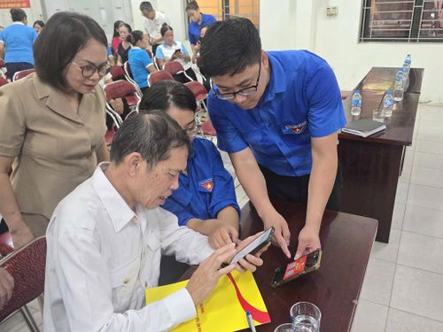 Đoàn viên phường hướng dẫn người dân thực hiện các thao tác trên điện thoại thông minh. Ảnh: Nguyễn Hương