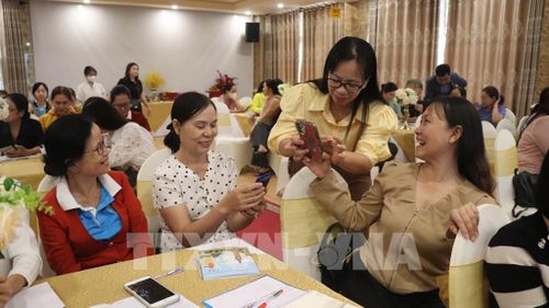 Đại diện Hội Liên hiệp phụ nữ thành phố hỗ trợ học viên thực hành ứng dụng AI trên điện thoại. Ảnh: Nguyễn Hằng - TTXVN