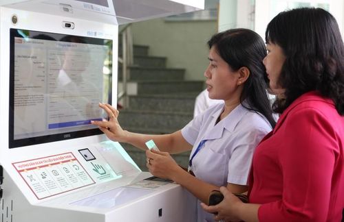 Hướng dẫn người dân sử dụng Kiosk tiếp đón thông minh tại Trạm Y tế xã Châu Phú. Ảnh: Minh Hải.