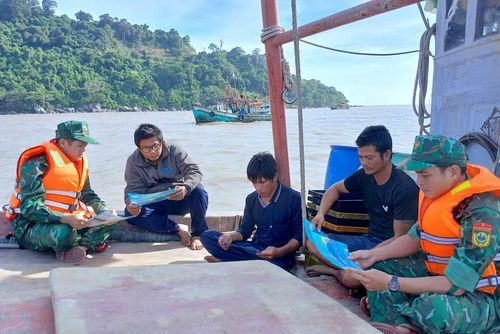 Thượng úy Nguyễn Trường Minh (bìa trái) cùng đồng nghiệp tuyên truyền pháp luật trên các tàu cá neo đậu quanh đảo Hòn Khoai. (Ảnh: ĐÌNH THẮNG)