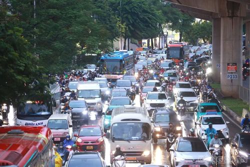 Dòng ô tô, xe máy nối dài trên đường Hồ Tùng Mậu. Trong cơn mưa tầm tã, người dân chật vật di chuyển giữa dòng phương tiện đông đúc.