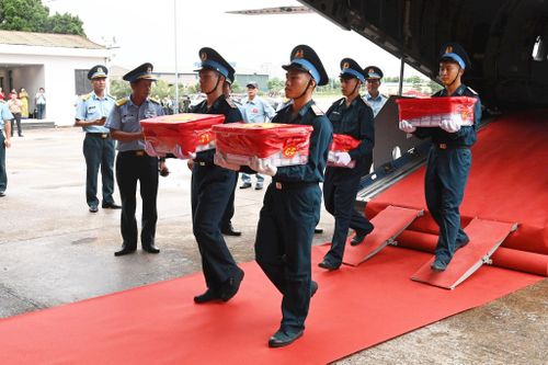 Cán bộ, chiến sĩ Quân chủng Phòng không - Không quân trang nghiêm đưa các thùng chứa mẫu sinh phẩm hài cốt liệt sĩ xuống máy bay. Ảnh: Hoàng Công