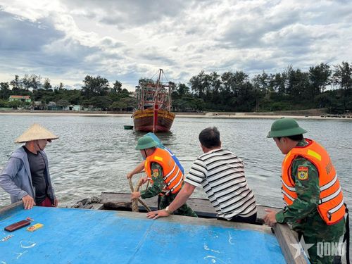 Cán bộ, chiến sĩ Đồn Biên phòng Cửa Tùng cùng người dân sử dụng dây thừng kéo tàu cá mắc cạn.