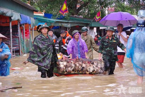 Cán bộ, chiến sĩ giúp các tiểu thương đưa hàng hóa khỏi khu vực ngập lụt.