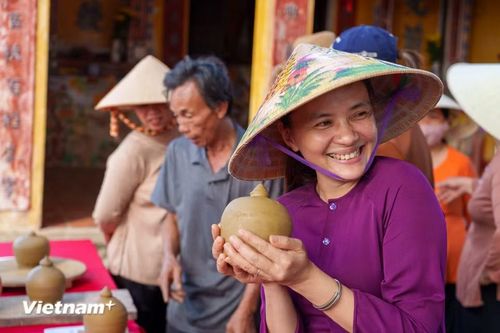 Nụ cười rạng rỡ của nữ nghệ nhân làng gốm Thanh Hà khi nâng niu sản phẩm gốm mộc vừa được vuốt nặn thành hình. (Ảnh: Thanh Phong/Vietnam+)