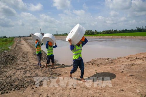 Công nhân tập kết vật liệu đến vị trí thi công gia tải nền đường dự án thành phần 2, cao tốc Châu Đốc - Cần Thơ - Sóc Trăng đoạn qua xã Thạnh Quới, thành phố Cần Thơ. Ảnh: Thanh Liêm - TTXVN