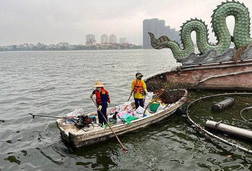 Công nhân vớt rác trên mặt hồ Tây. Ảnh: Bảo Hân